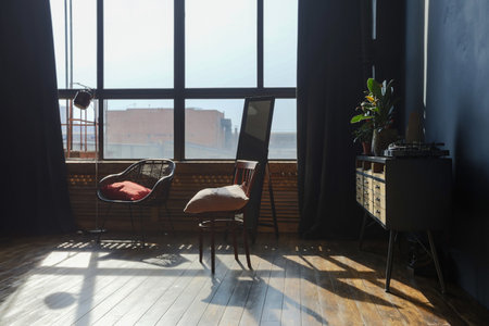 dark interior of a modern stylish huge open-plan loft-style studio apartment with columns and high ceilings. dark blue primed walls are decorated with wood. sunlight enters through huge windows.の写真素材