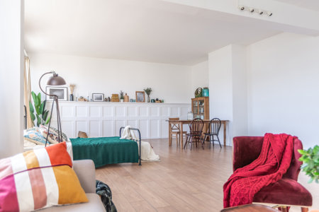 Vintage studio apartment interior in light colors in old style. huge room with large windows with a living room area and a bedroom area. direct sunlight inside.の写真素材