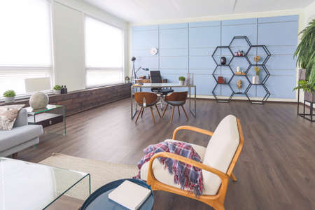 Modern trendy creative design of a personal studio office with a seating area in the style of minimalism in blue and beige colors with large windows and daylightの写真素材