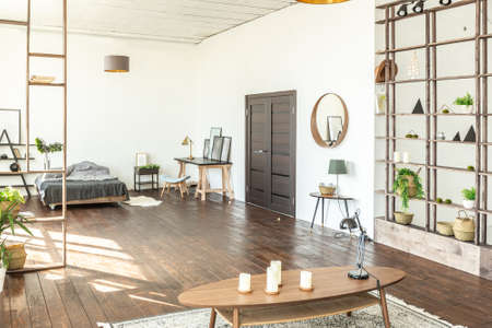 spacious studio apartment decorated with wood and white. Minimalist design with huge windows in the...