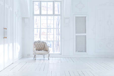 Spacious bright living room with a stylish modern design with elements of antique decor and beautiful chic furniture in the old style and many floor-to-ceiling windowsの写真素材