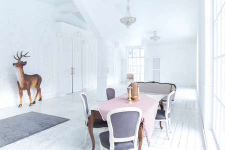 Spacious bright living room with a stylish modern design with elements of antique decor and beautiful chic furniture in the old style and many floor-to-ceiling windowsの写真素材