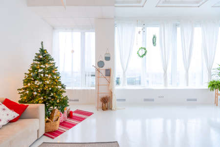 large very bright spacious stylish open plan Bali style apartment with hanging bed and panoramic windows. white floor and walls, simple wooden furniture. decorated with a christmas treeの写真素材