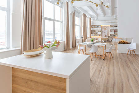 interior design spacious bright studio apartment in Scandinavian style and warm pastel white and beige colors. trendy furniture in the living area and modern details in the kitchen area.の写真素材