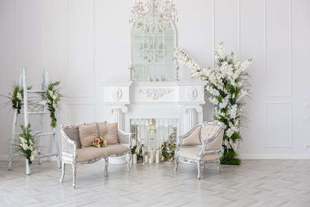 luxurious bright spacious guest room with beautiful chic furniture a huge floor-to-ceiling window in a royal style is decorated with green plants, white walls with stucco and a fireplaceの写真素材