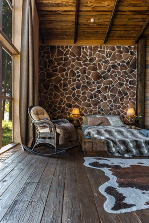 dark cozy interior of big country wooden house, wooden furniture and animal furs. huge panoramic window and very high ceiling.の写真素材