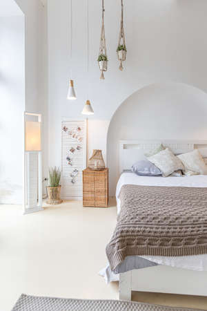 Fashionable modern interior of a light studio apartment with wooden columns in the loft style, decorated with brick, marble and wood with stylish furniture and white wallsの写真素材