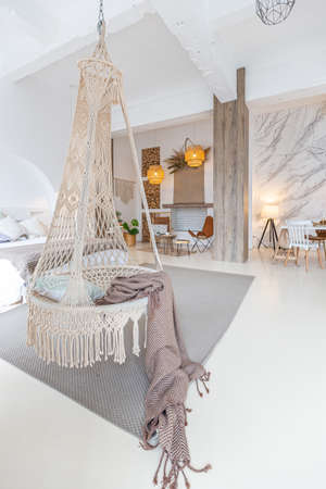 Fashionable modern interior of a light studio apartment with wooden columns in the loft style, decorated with brick, marble and wood with stylish furniture and white wallsの写真素材