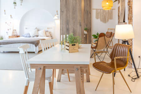 Fashionable modern interior of a light studio apartment with wooden columns in the loft style, decorated with brick, marble and wood with stylish furniture and white wallsの写真素材