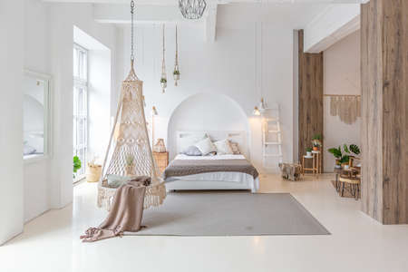 Fashionable modern interior of a light studio apartment with wooden columns in the loft style, decorated with brick, marble and wood with stylish furniture and white wallsの写真素材