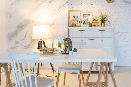 Fashionable modern interior of a light studio apartment with wooden columns in the loft style, decorated with brick, marble and wood with stylish furniture and white wallsの写真素材