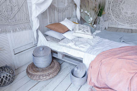 Balinese style bedroom interior. canopy bed with lots of textiles for decoration and wicker items in...