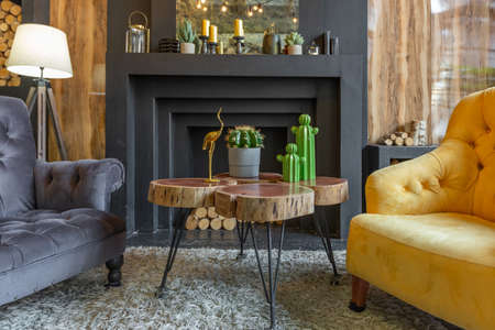 dark brutal interior of sitting room decorated with wooden logs. yellow and gray soft armchairs,...