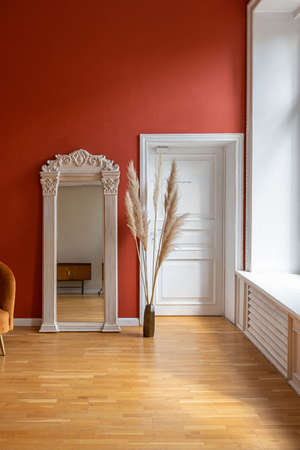 antique vintage interior in 19th century style living room with bright red walls, wood floor and direct sunlight inside the room.の写真素材