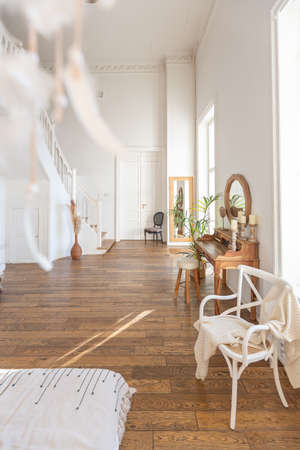 modern interior of a bright room in a two-storey apartment with decorative items in bali style with a balcony. white walls, wood floors and vintage furnitureの写真素材