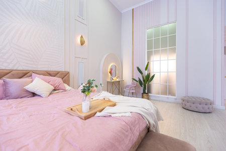 luxurious modern bedroom interior of an expensive spacious light stylish apartment. upholstered furniture and decorative lighting, soft pastel colors and cozy atmosphereの写真素材