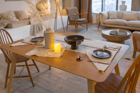 cozy warm home interior of a chic country house with an open plan, wood finishes, warm colors and a family hearth. view of the dining area, table and table settingの写真素材