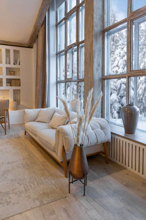 cozy warm home interior of a chic country chalet with a huge panoramic window overlooking the winter...