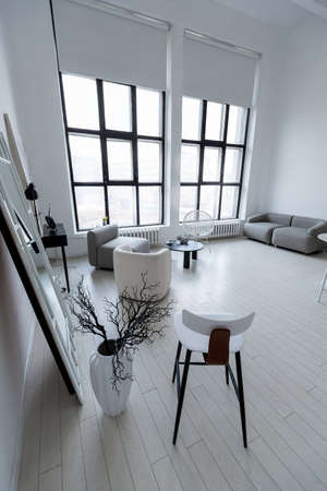 modern minimalistic interior design of light bright monochrome room with black and white furniture, clean white walls and huge windowsの写真素材