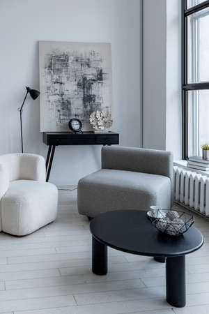 modern minimalistic interior design of light bright monochrome room with black and white furniture, clean white walls and huge windowsの写真素材