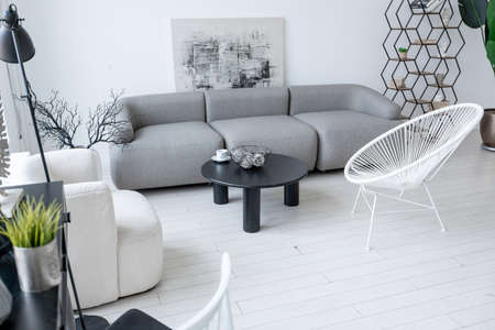 modern minimalistic interior design of light bright monochrome room with black and white furniture, clean white walls and huge windowsの写真素材