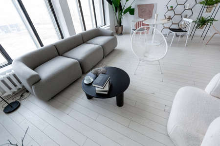 modern minimalistic interior design of light bright monochrome room with black and white furniture, clean white walls and huge windowsの写真素材