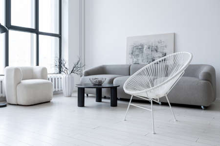 modern minimalistic interior design of light bright monochrome room with black and white furniture, clean white walls and huge windowsの写真素材