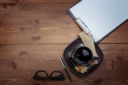 Cup of coffee, notebook and glasses on a wooden table.の写真素材