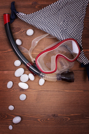 Diving mask, snorkel and white stones on wooden backgroundの写真素材