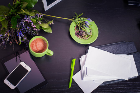 A cup of coffee on a black table with a phone and a notebookの写真素材