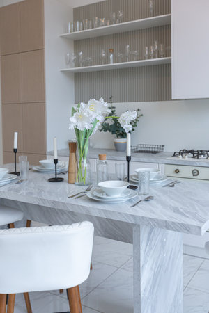 close view kitchen with dinning marble table and hight bar stools in minimalistic light elegant luxury design of a modern spacious studio apartment in soft pastel beige colorsの写真素材