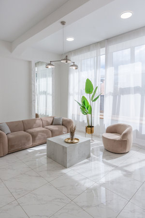 living room with soft beige furniture in a light luxury interior design of a modern apartment in a minimalist style with marble trim and huge windows. daylight inside.の写真素材