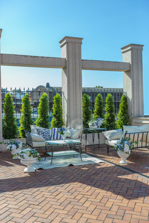 a chic terrace of a country house with wrought iron furniture, vases with flowers and columns on a bright summer sunny dayの写真素材