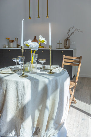 romantic table is served for two in the kitchen in a bright open-plan apartment in a modern style with light walls and wooden floors.の写真素材