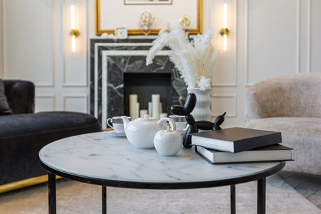 close-up of a tea table setting in a modern living room with a marble fireplace in a chic bright...