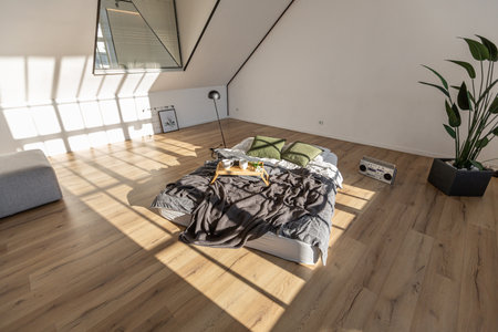 minimalist stylish interior of white simple bedroom with window in ceiling and sun rays without peopleの写真素材