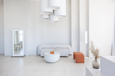 modern pure white interior design of a spacious sitting room with soft stylish furniture. Large window frame creating a serene atmosphere during daylight.の写真素材