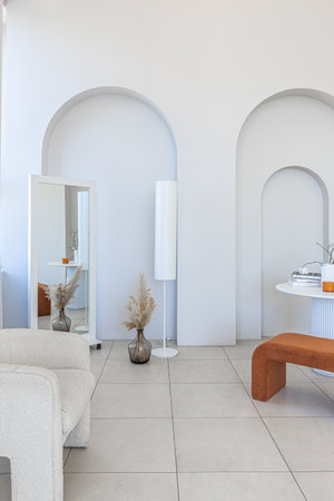 modern pure white interior design of a spacious sitting room with soft stylish furniture. Large window frame creating a serene atmosphere during daylight.の写真素材