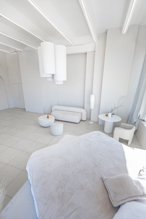 modern pure white interior design of a spacious sitting room with soft stylish furniture. Large window frame creating a serene atmosphere during daylightの写真素材