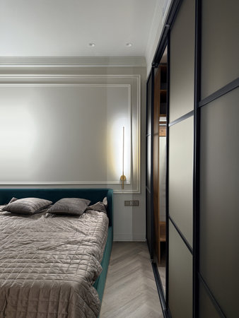 This cozy bedroom features a plush bed adorned with soft pillows, complemented by a sleek, modern closet illuminated from within, enhancing the room's ambiance and elegance.の写真素材