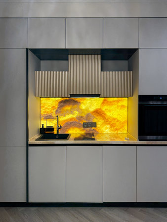 A stylish kitchen features minimalist cabinetry and a vibrant backsplash, creating a focal point in a modern apartment. The open layout enhances the space's functionality and appeal.の写真素材
