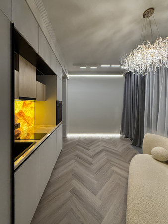 A contemporary living area features a plush, rounded sofa with stunning chandelier lighting. The muted color scheme and sleek lines create an inviting atmosphere.の写真素材