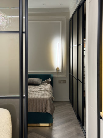 This cozy bedroom features a plush bed adorned with soft pillows, complemented by a sleek, modern closet illuminated from within, enhancing the room's ambiance and elegance.の写真素材