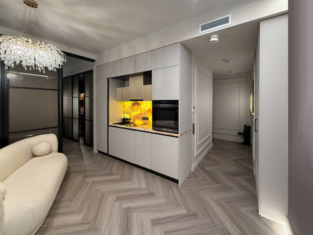 A stylish kitchen features minimalist cabinetry and a bright yellow backsplash, creating a vibrant focal point in a modern apartment. The open layout enhances the space's functionality and appeal.の写真素材