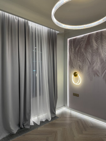 A stylish interior showcases a corner with wooden shelves holding decorative items, soft drapes, and warm ambient lighting, creating a welcoming atmosphere.の写真素材