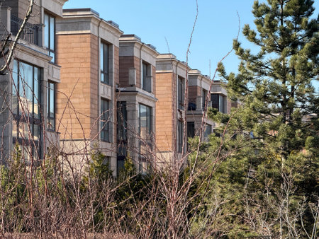 modern, multi-story residential buildings with large windows and beige stone facades. The architecture is elegant and contemporary. The weather is clear and sunny, with a bright blue skyの写真素材