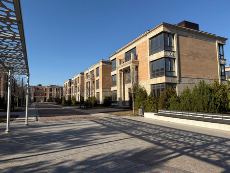 modern, multi-story residential buildings with large windows and beige stone facades. The architecture is elegant and contemporary. The weather is clear and sunny, with a bright blue skyの写真素材