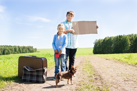  cute girl and boy with dog and suitcase on roadの写真素材