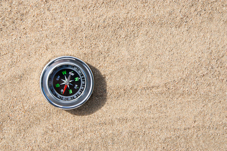 compass in the sand lit by the sunの写真素材