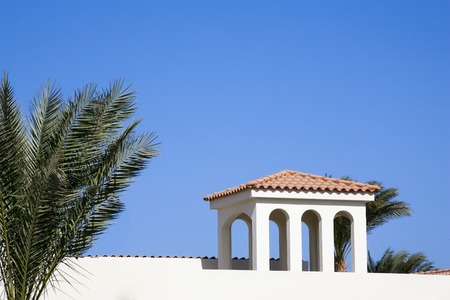 Medieval house in the Romanesque style, surrounded by palm trees.